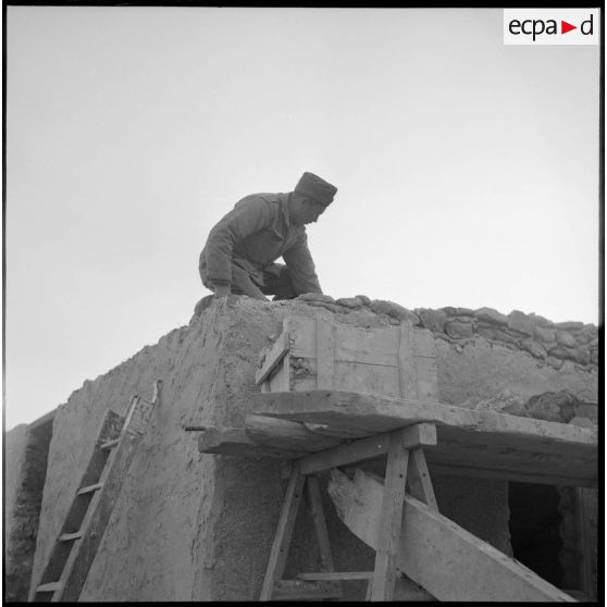 Un soldat sur le toit d'une mechta en chantier en Algérie.