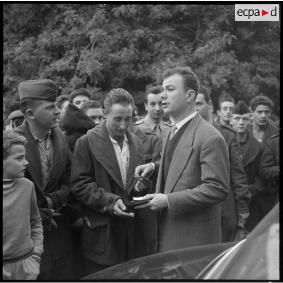 Le comédien Fernand Raynaud distribue des autographes devant l'hôpital militaire Maillot à Alger.