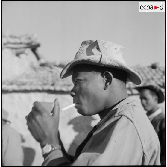 Portrait d'un militaire allumant une cigarette.