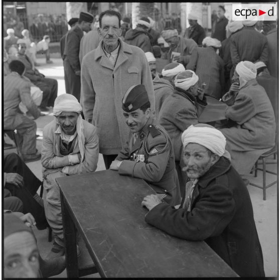 Un tirailleur attablé avec des civils.