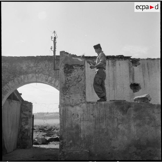 Militaire cassant un pan de mur.