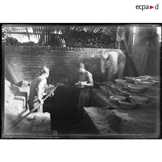 On enfourne les boules de pains pour la cuisson. [légende d'origine]