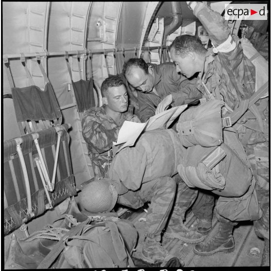 Un briefing tardif entre le médecin et le navigateur à l'intérieur d'un avion de transport Nord 2501, avant l'arrivée sur la DZ de Port-Saïd et le largage de la deuxième vague du 2e RPC.