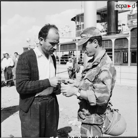 Un parachutiste français contrôle l'identité d'un civil égyptien sur le quai du ferry assurant la traversée du canal de Suez.
