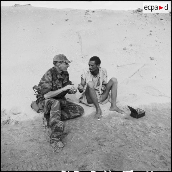 Le 2e classe Michel Nicod du 2e RPC (régiment de parachutistes coloniaux) offre du feu à un Egyptien, au cours d'une reconnaissance armée en jeep à l'est de Port-Fouad, le long de la côte.