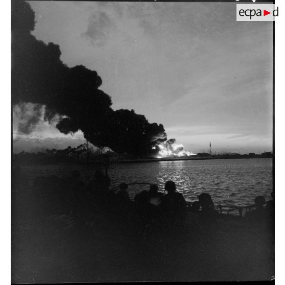 La nuit tombée, l'incendie du dépôt de carburant à Port-Saïd éclaire le plan d'eau des bassins charbonniers.