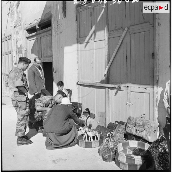 Trois parachutistes français s'intéressent aux articles d'un marchand ambulant de Port-Saïd.