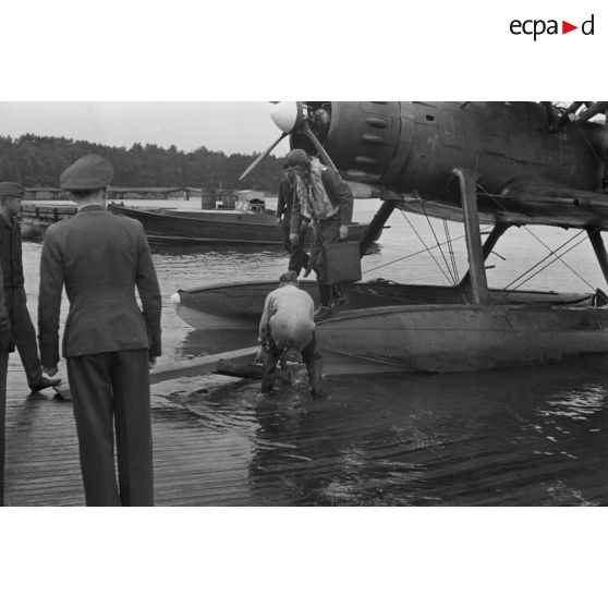 Un pilote d'hydravion Arado Ar-95 descend de son appareil, une mallette à la main, des officiers de la Luftwaffe l'attendent.