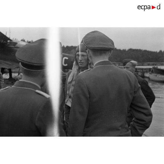 Un pilote d'hydravion Arado Ar-95 descend de son appareil, une mallette à la main, des officiers de la Luftwaffe l'attendent.