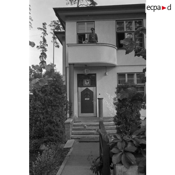 Un Oberfeldwebel du See-Aufklaerungsgruppe-125 se tient au balcon d'une maison réquisitionnée.