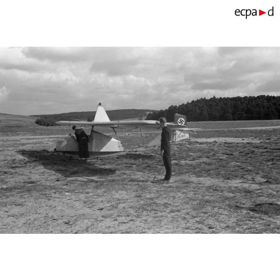 Un jeune membre du N.S.F.K. aide son camarade installé à bord d'un planeur léger Schulgleiter SG 38.
