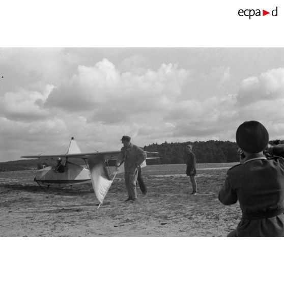 Un jeune membre du N.S.F.K. aide son camarade installé à bord d'un planeur léger Schulgleiter SG 38.
