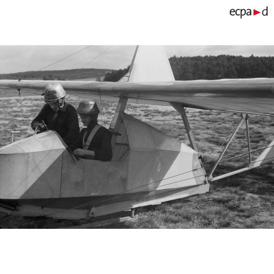 Un jeune membre du N.S.F.K. aide son camarade installé à bord d'un planeur léger Schulgleiter SG 38.