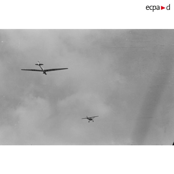 Un Morane-230 en vol, tracte un planeur monoplace de type DFS Habicht, du N.S.F.K. (Nationalistischen Flieger-Korps)
