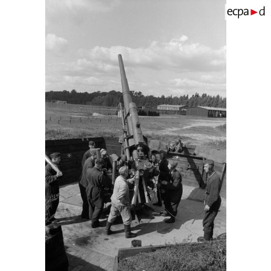 Mise en batterie d'une pièce de 8,8-cm-FlaK-18-L56, placée dans un abri en bois.