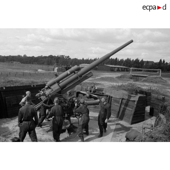Mise en batterie d'une pièce de 8,8-cm-FlaK-18-L56, placée dans un abri en bois.