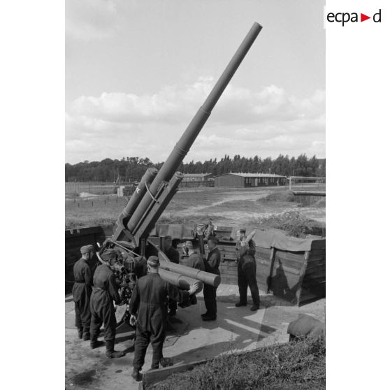 Mise en batterie d'une pièce de 8,8-cm-FlaK-18-L56, placée dans un abri en bois.