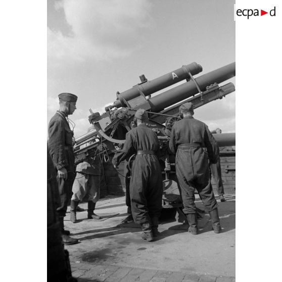 Mise en batterie d'une pièce de 8,8-cm-FlaK-18-L56, placée dans un abri en bois.