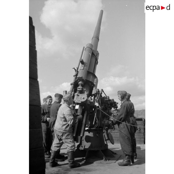 Mise en batterie d'une pièce de 8,8-cm-FlaK-18-L56, placée dans un abri en bois.