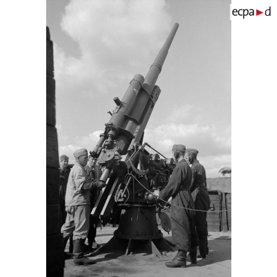 Mise en batterie d'une pièce de 8,8-cm-FlaK-18-L56, placée dans un abri en bois.