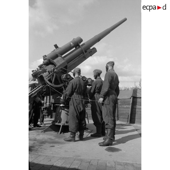 Mise en batterie d'une pièce de 8,8-cm-FlaK-18-L56, placée dans un abri en bois.