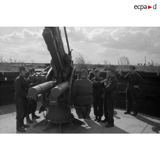 Mise en batterie d'une pièce de 8,8-cm-FlaK-18-L56, placée dans un abri en bois.