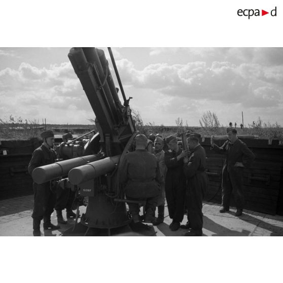Mise en batterie d'une pièce de 8,8-cm-FlaK-18-L56, placée dans un abri en bois.