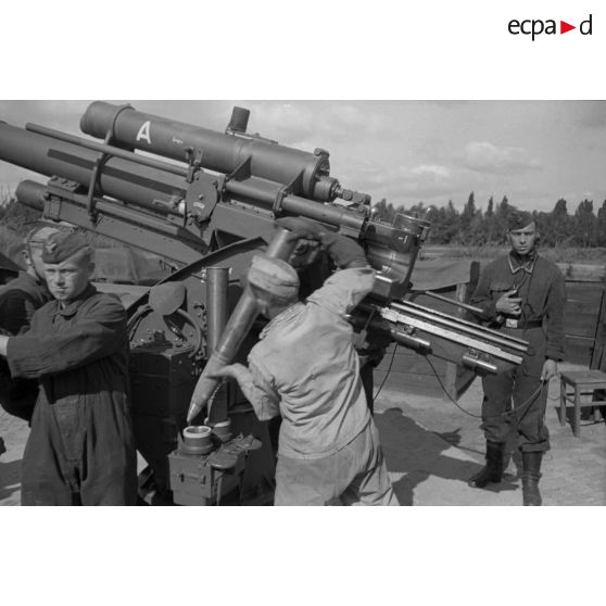 Mise en batterie d'une pièce de 8,8-cm-FlaK-18-L56, placée dans un abri en bois.