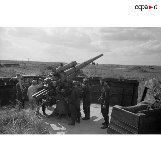 Mise en batterie d'une pièce de 8,8-cm-FlaK-18-L56, placée dans un abri en bois.