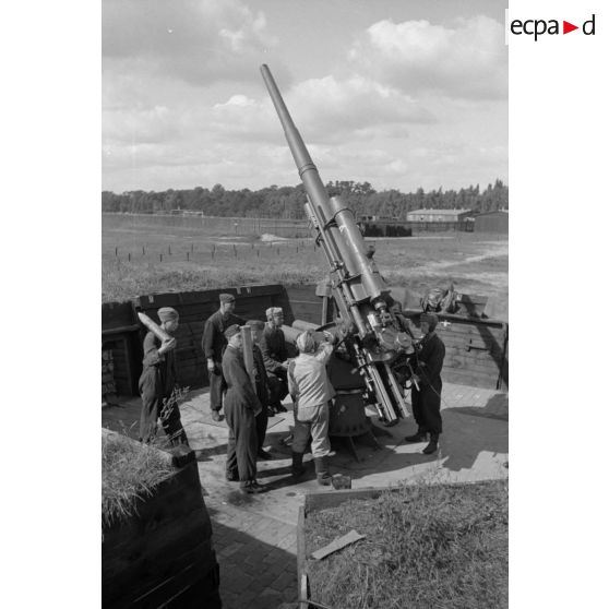 Mise en batterie d'une pièce de 8,8-cm-FlaK-18-L56, placée dans un abri en bois.