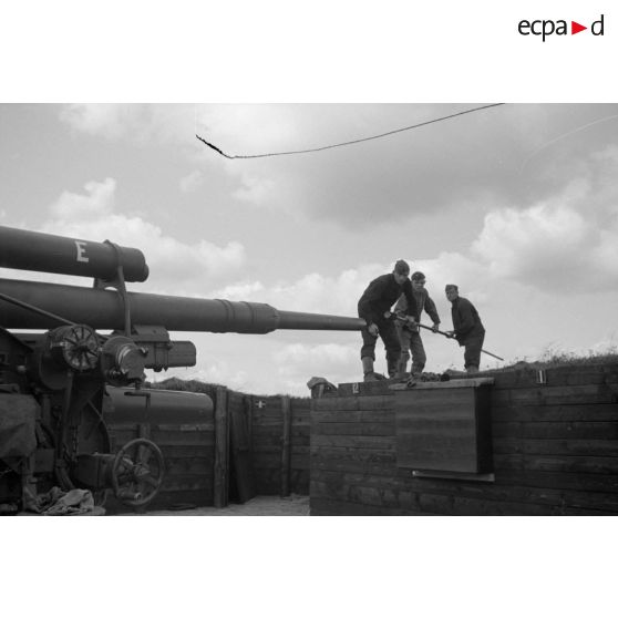 Trois servants d'une pièce de 8,8 cm FlaK-18-L56 nettoient le tube de leur canon avec un écouvillon.