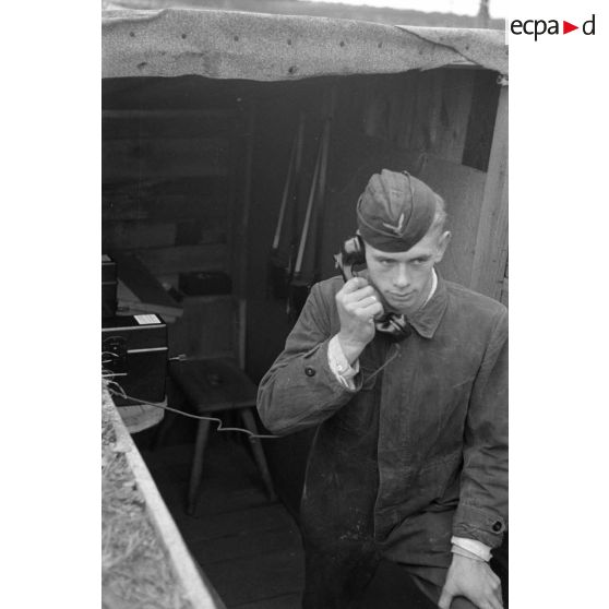 Un jeune soldat allemand de la Flak, dans un abri, parle au téléphone.
