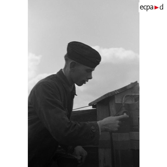Un jeune artilleur allemand de la FlaK appuie sur le bouton de la sirène d'alarme.