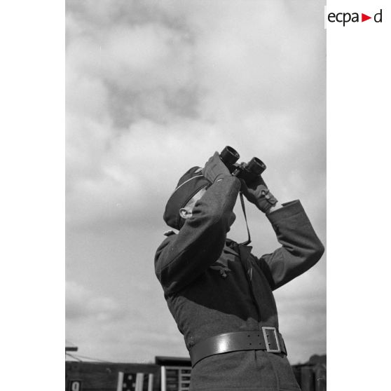 Un Leutnant de la DCA de l'armée de l'air allemand (FlaK) aux jumelles et donne des indications de direction à des servants de télémètre.