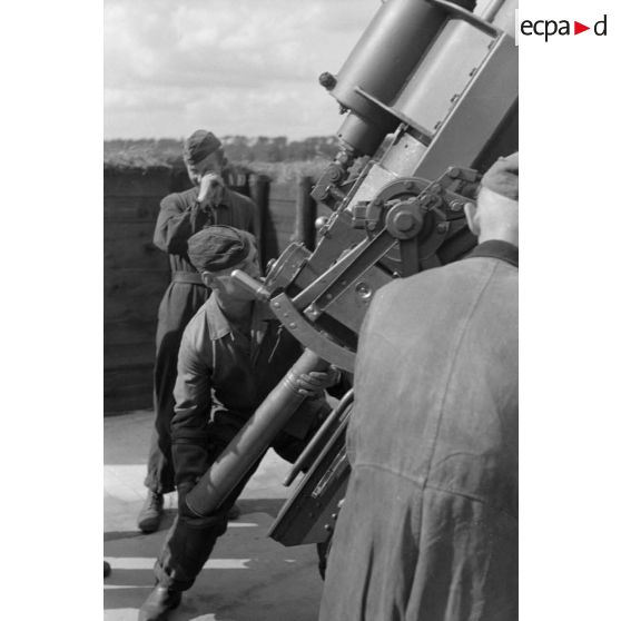 Un servant d'une pièce de 8,8 cm FlaK-18-L56 introduit un obus dans la culasse du canon.