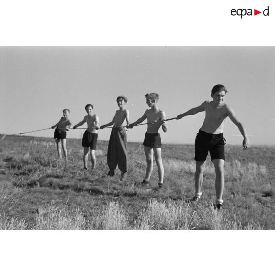 Des jeunes membres du Nationalsozialistischen Flieger-Korps (N.S.F.K.) tirent la corde destinée à donner la vitesse nécessaire au décollage d'un planeur léger.