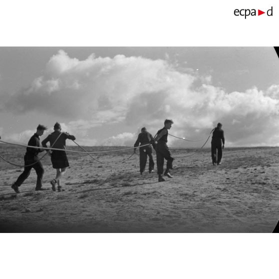 Des jeunes membres du Nationalsozialistischen Flieger-Korps (N.S.F.K.) tirent des cordes destinées à donner sa vitesse ascensionnelle à un planeur léger.