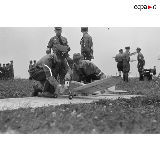 Deux membres des Hitlerjugend dont au moins un appartenant au district "Süd Franken", installent leur modèle réduit d'avion sur son aire d'envol, aidés par un cadre du N.S.F.K.
