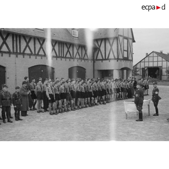 Lors d'une prise d'armes, des membres de la Hitlerjugend, au garde-à-vous devant deux cadres du N.S.F.K.