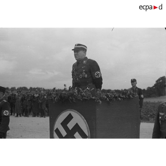 L'Obergruppenführer Karl Sauke du N.S.F.K. debout derrière une tribune, prononce un discours.