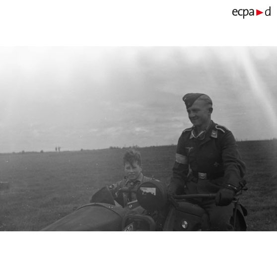 Un aviateur allemand (sous-officier) conduit un membre des Hitlerjugend dans son side-car.