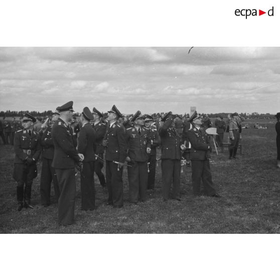 Un groupe d'officiers de la Luftwaffe regardent les évolutions des modèles réduits d'avions, des membres de la Hitlerjugend.