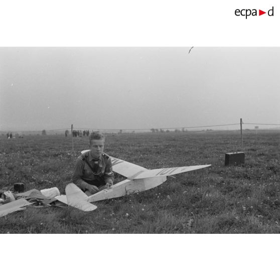 Un membre de la Hitlerjugend accroupi devant son modèle réduit d'avion.