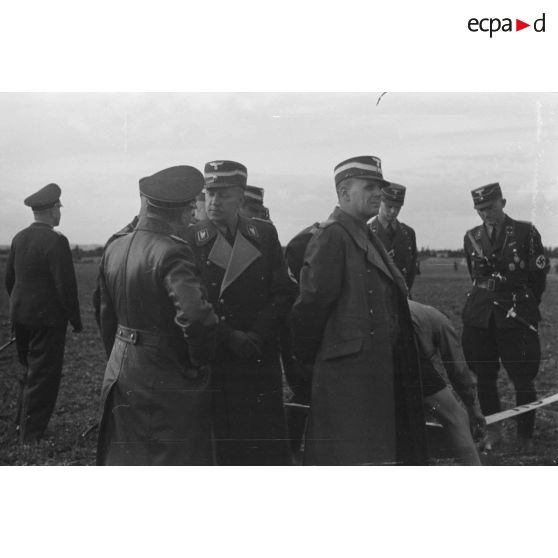 Des responsables du N.S.F.K. et des officiers de la Luftwaffe regardent les modèles réduits d'avions présentés au sol.