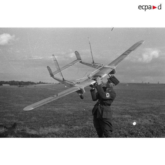 Un officier du Nationalistischen Flieger-Korps (N.S.F.K.) tient à bout de bras un modèle réduit d'avion, d'un genre particulier (bipoutre).