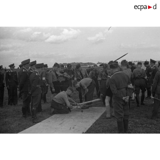 Deux membres de la Hitlerjugend s'apprète à faire décoller leur modèle réduit, sous les regards de membres de la Luftwaffe, de la Hitlerjugend et du N.S.F.K.