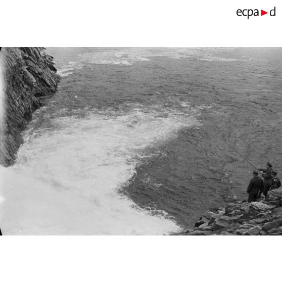 Des officiers de la Luftwaffe pèchent dans un cours d'eau montagneux en Finlande.