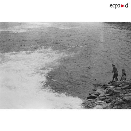 Des officiers de la Luftwaffe pèchent dans un cours d'eau montagneux en Finlande.