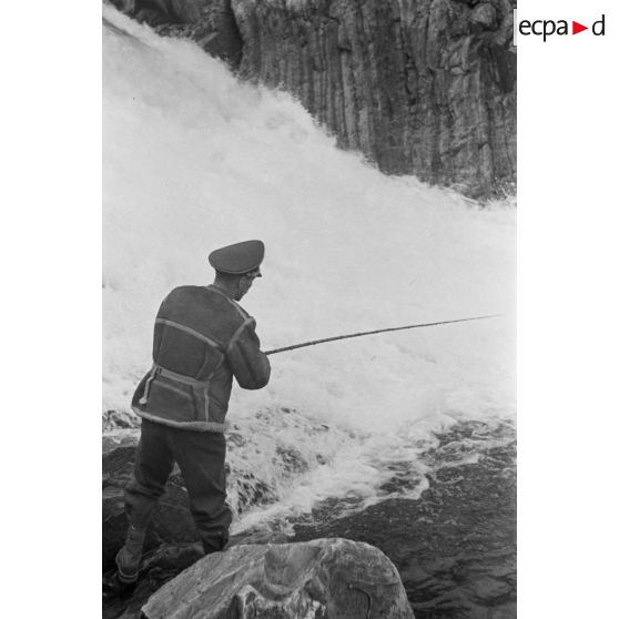 Des officiers de la Luftwaffe pèchent dans un cours d'eau montagneux en Finlande.