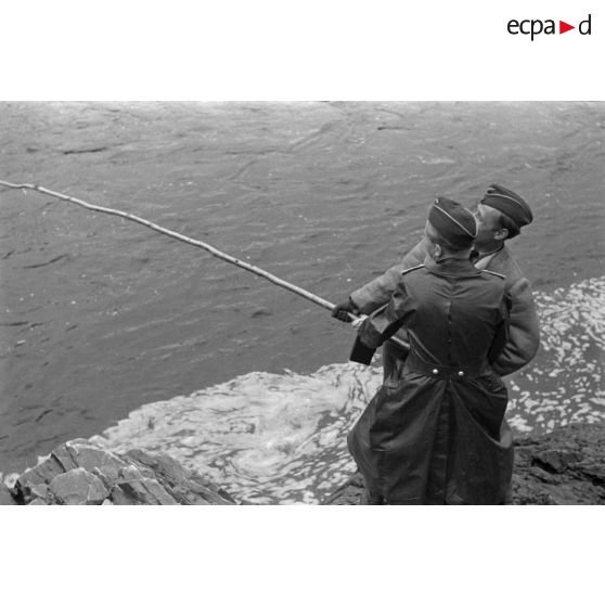 Des officiers de la Luftwaffe pèchent dans un cours d'eau montagneux en Finlande.